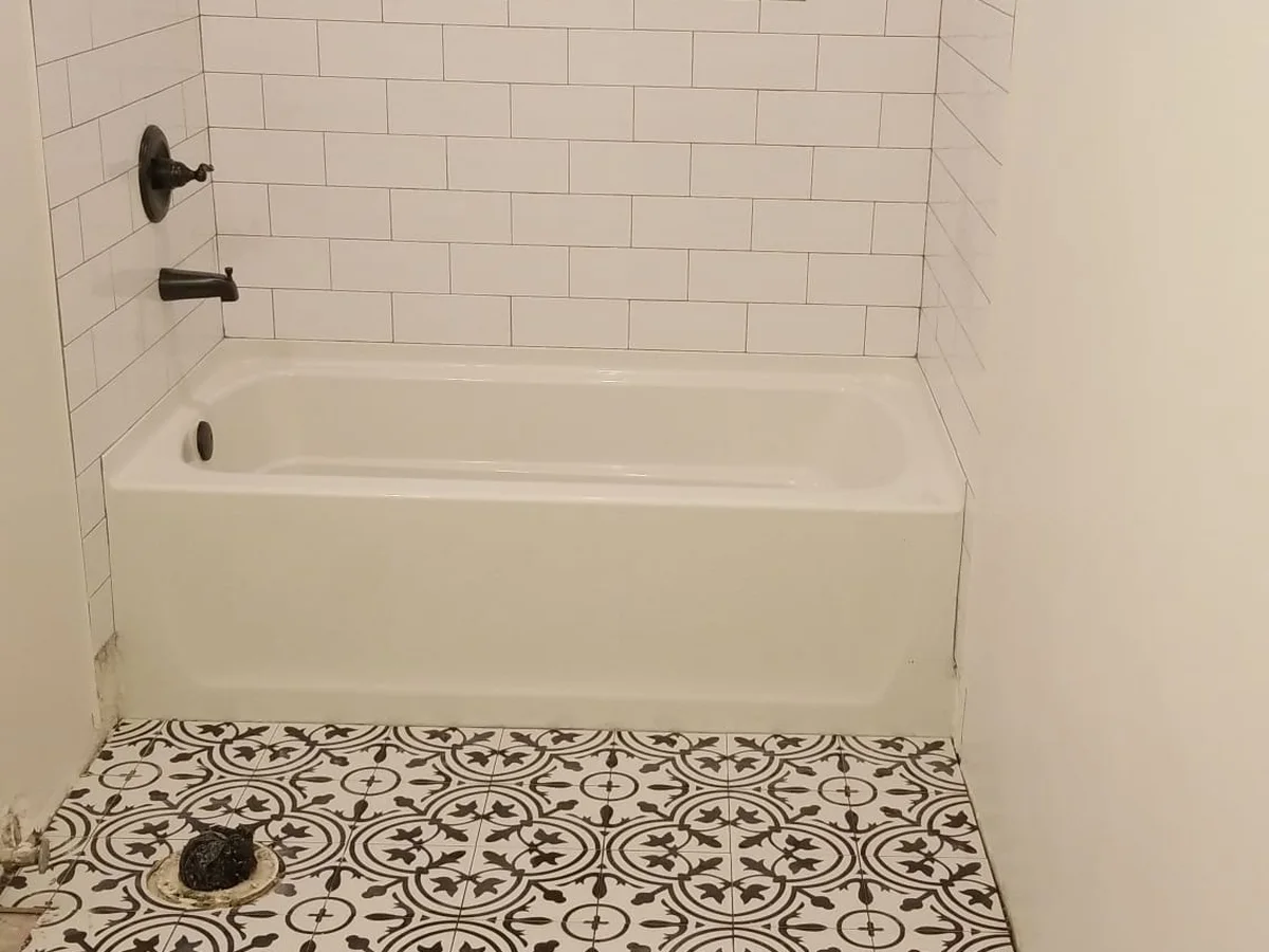 Subway-tile tub surround over a patterned tile floor